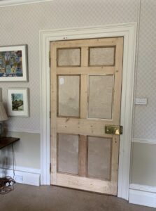 Fire-clad Craigmyle door rehung in its frame, ready for decoration